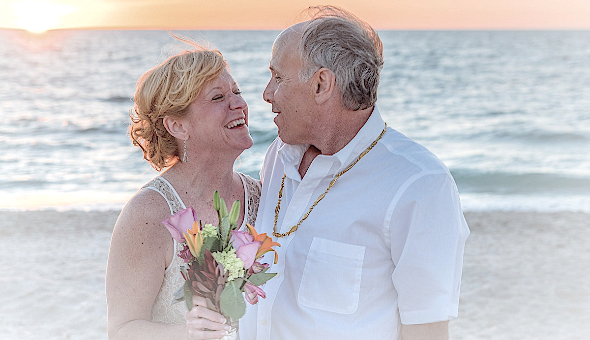 Senior couple enjoying the beach at sunset after their jewish wedding with a rabbi in Europe.